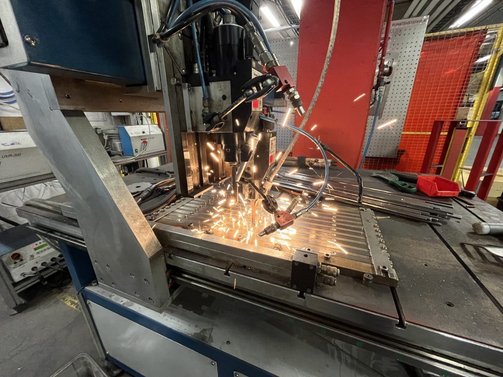 Bultskjutning i plåt där bultar fästs i metallkomponent i produktion